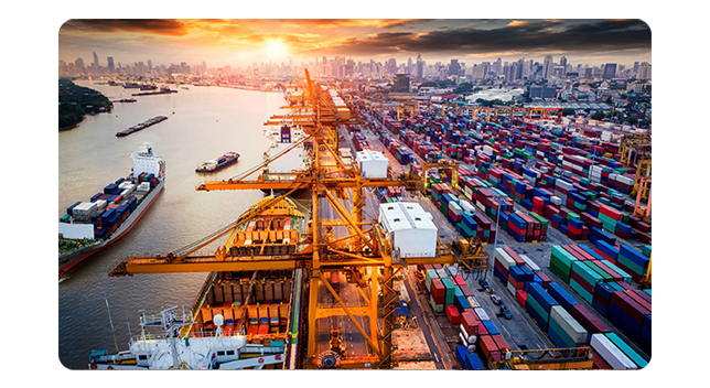 Trucks transporting cargo to a large shipping boat that is docked and loading