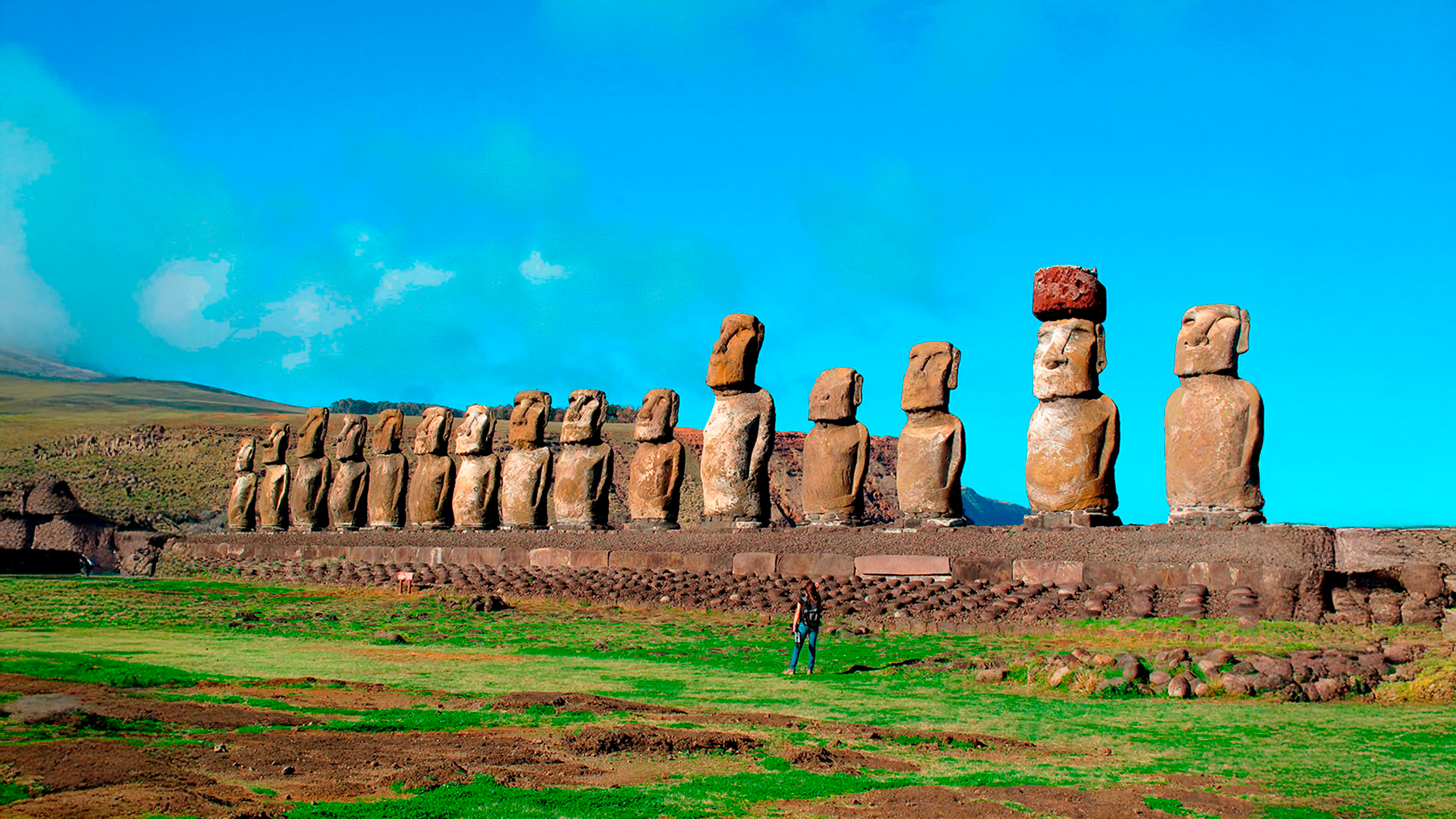 Three young adults smiling while backpacking through a field