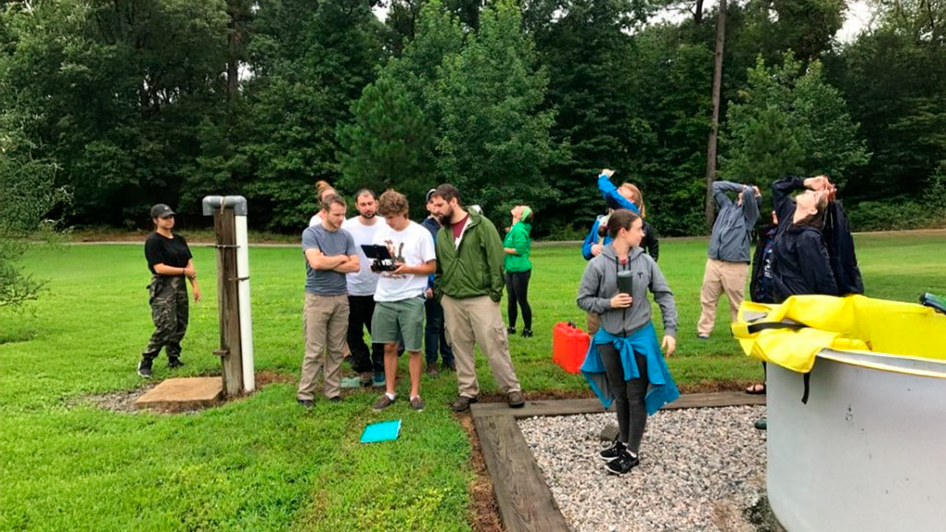 Three young adults smiling while backpacking through a field