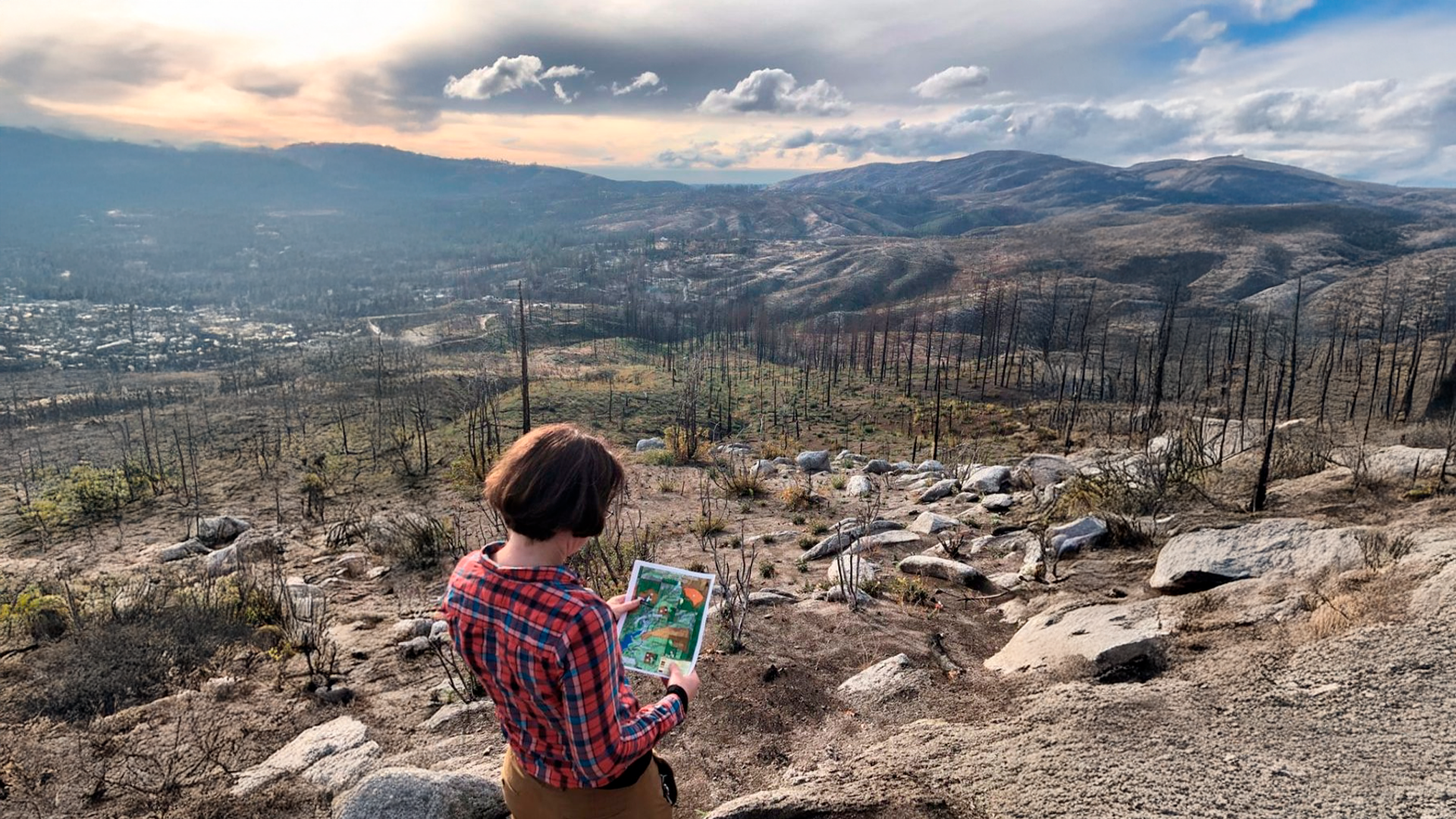 Three young adults smiling while backpacking through a field
