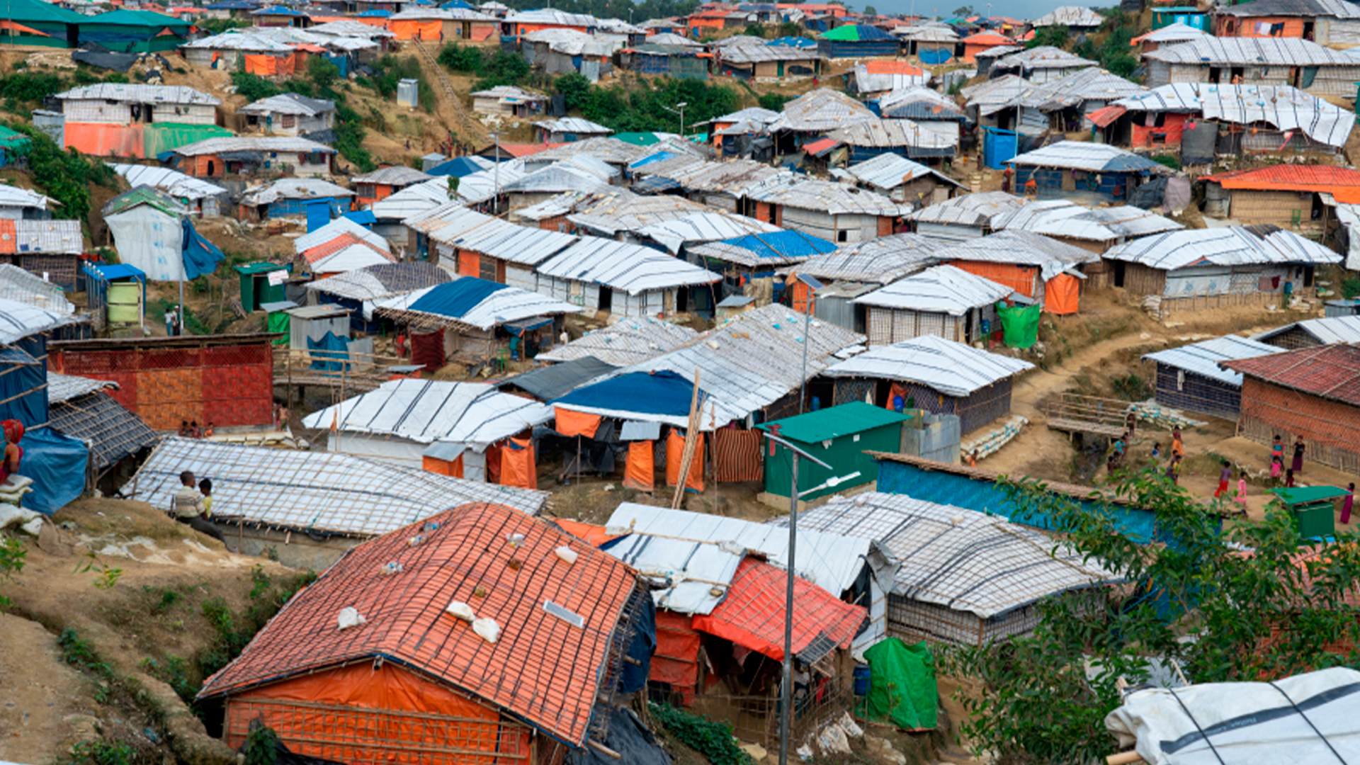 Three young adults smiling while backpacking through a field