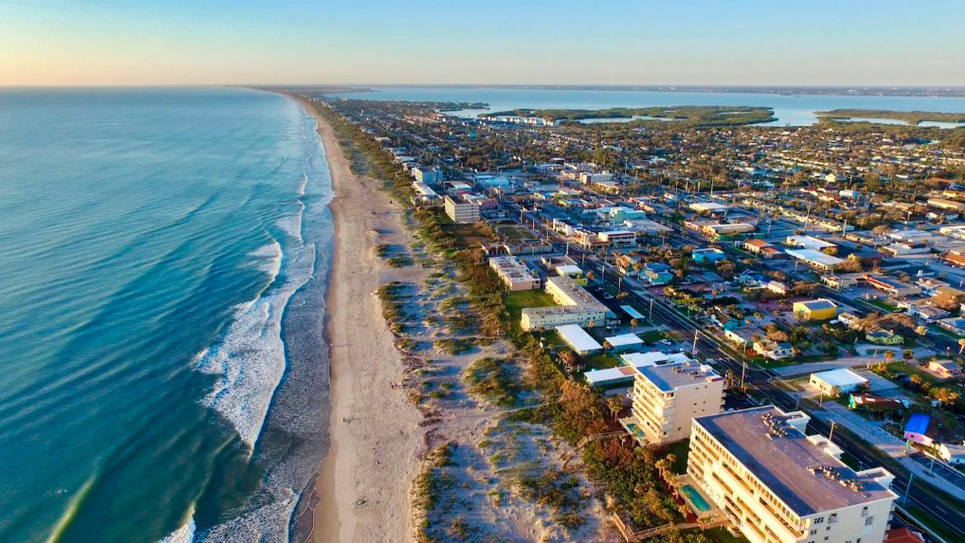 Three young adults smiling while backpacking through a field