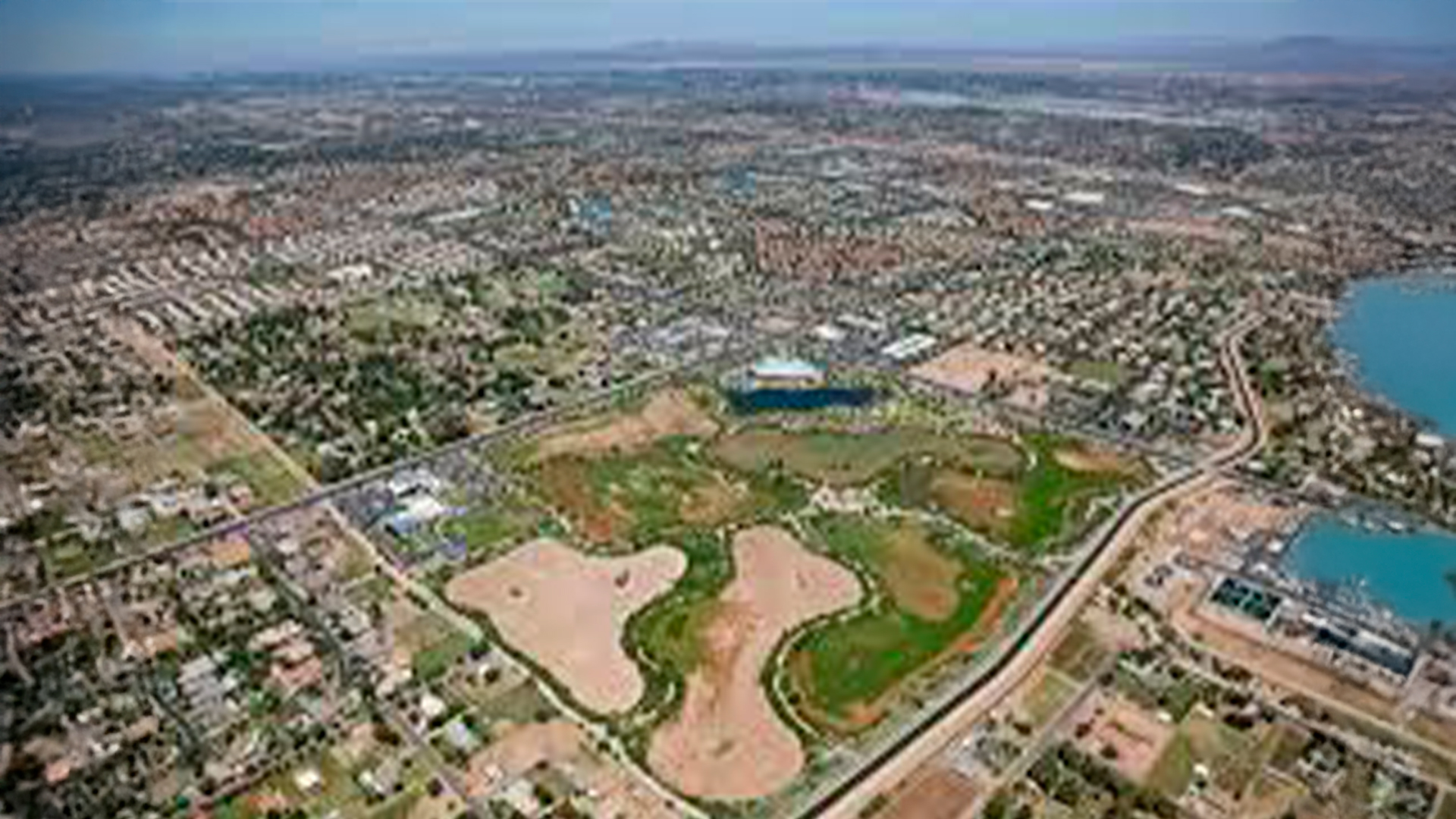 Three young adults smiling while backpacking through a field