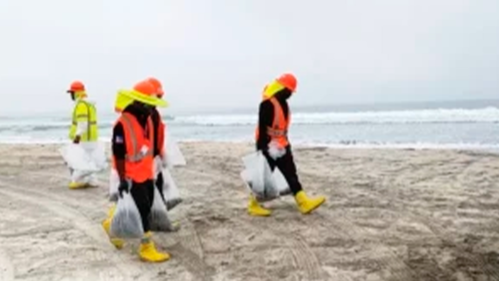 Three young adults smiling while backpacking through a field