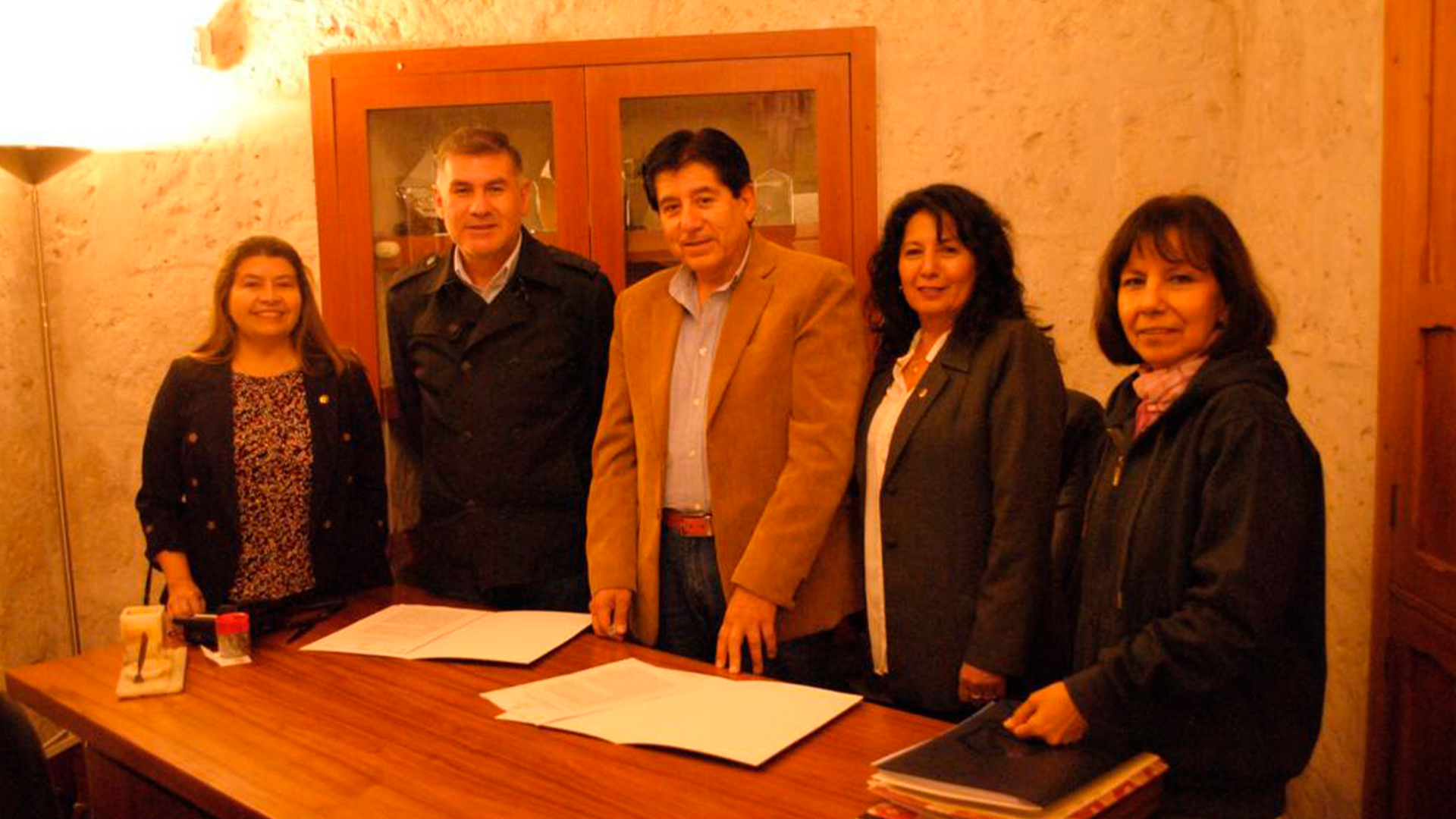 Three young adults smiling while backpacking through a field