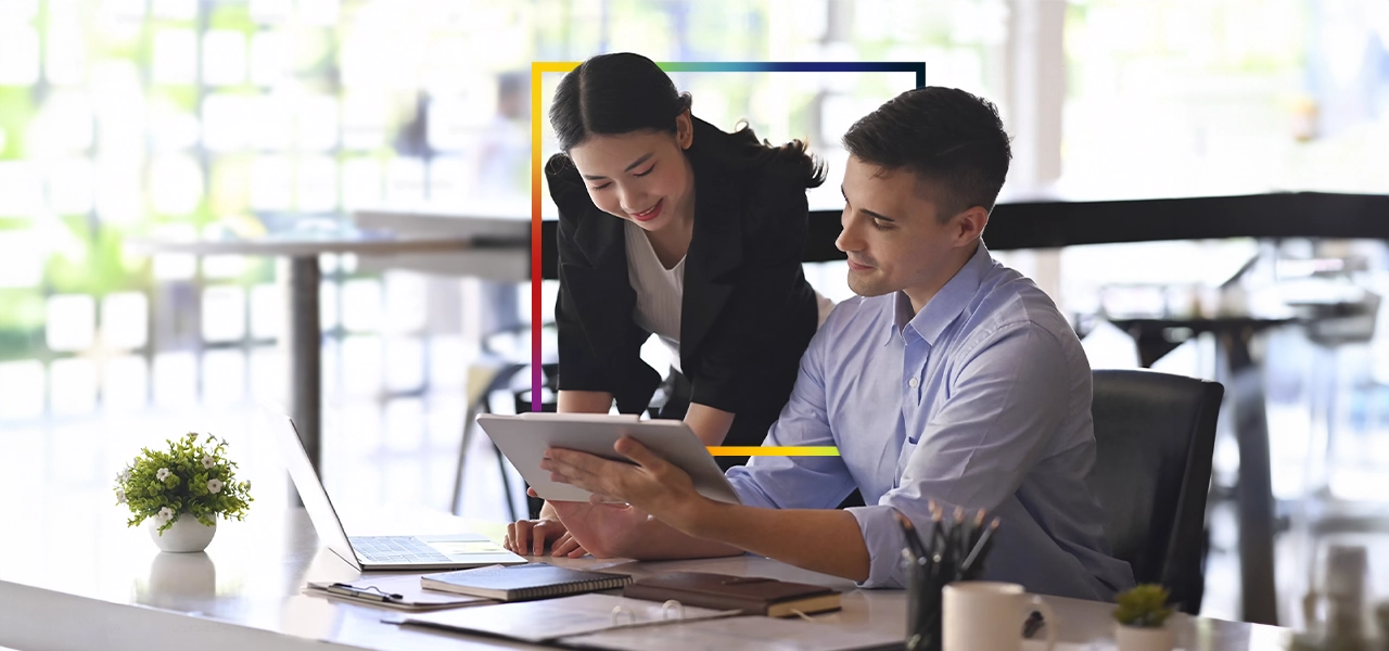 Dos personas que llevan ropa de invierno y equipo de seguridad naranja quitando la nieve acumulada a lo largo de una carretera transitada