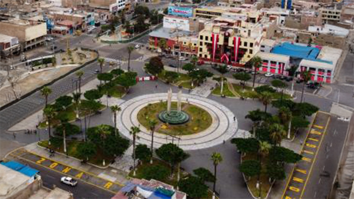 Árboles esbeltos dispersos silueteados en negro contra una puesta de sol rosa y naranja brillante en un gran campo marrón claro