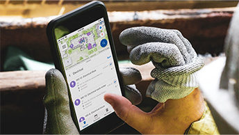 Primer plano de una mano usando un teléfono móvil para recopilar datos de activos sobre el terreno
