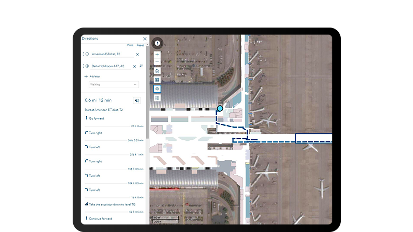 Pantalla de una tableta que muestra una imagen aérea de una terminal de aeropuerto con indicaciones de giro a la izquierda