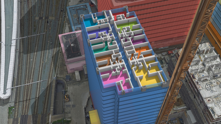 Vista aérea de un edificio ilustrado sin techo , lo que deja al descubierto el diseño de las habitaciones, cada una de ellas numerada y en un color diferente