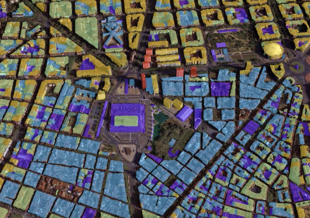 Vista aérea de edificios 3D con tonos de color amarillo, azul, verde y morado, donde también aparecen carreteras y una zona verde abierta