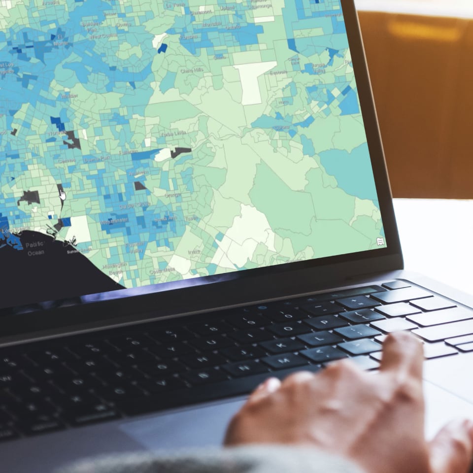 Hands typing on a laptop displaying a blue and green colored map of Southern California that shows hot spots
