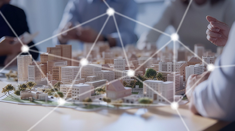 Modelo hecho a mano pequeño de una ciudad que descansa sobre una mesa de reuniones rodeada por personas con camisa con cuello y una red de puntos y líneas interconectados encima